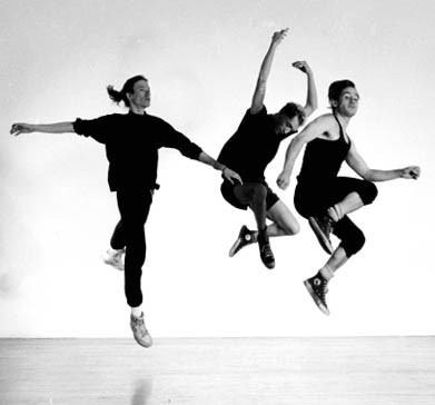 three male dancers in black jump in the air